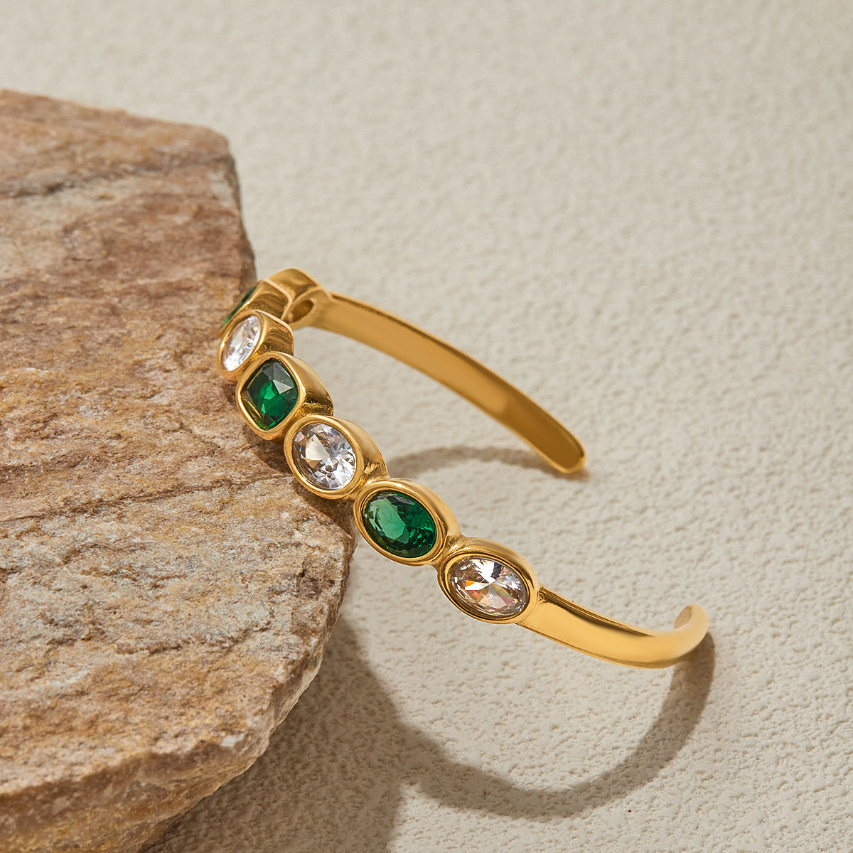 Close-up of gold bracelet with alternating green and clear stones for daily glam.