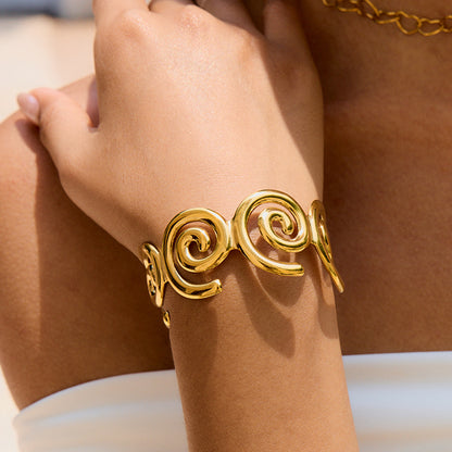 Bold gold swirl bangle styled with white top under sunlight