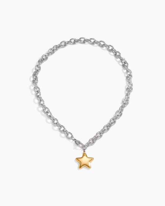 Silver chain bracelet with a gold star charm on a white background