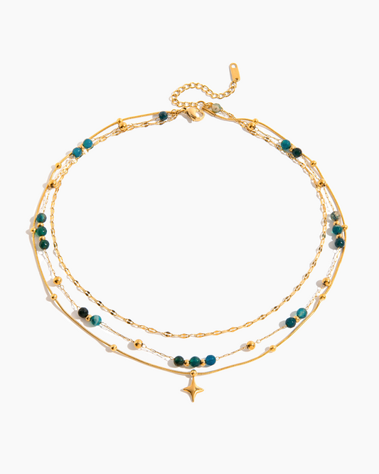 Gold bracelet with green beads on a white background