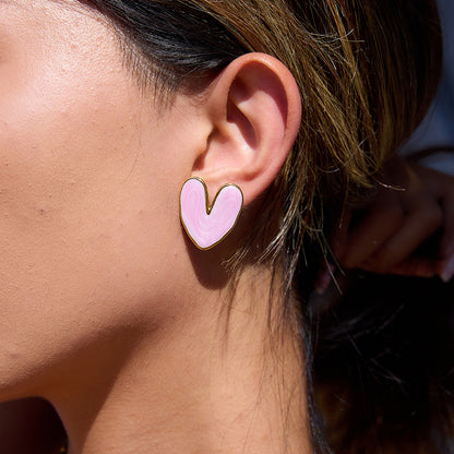 Model wearing pink enamel heart earrings on sunny day