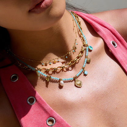 Gold star drop necklace worn by model with pink dress