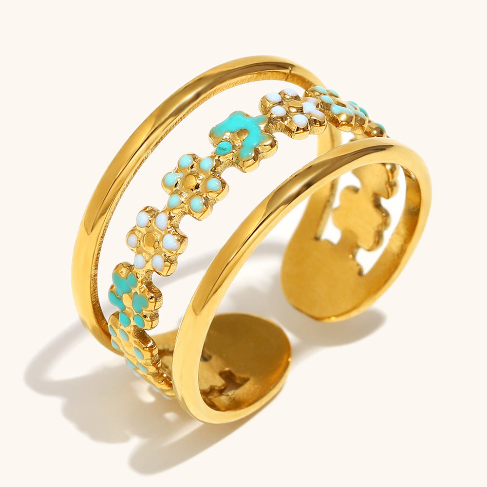Delicate green enamel floral open ring in gold, resting on natural stone.
