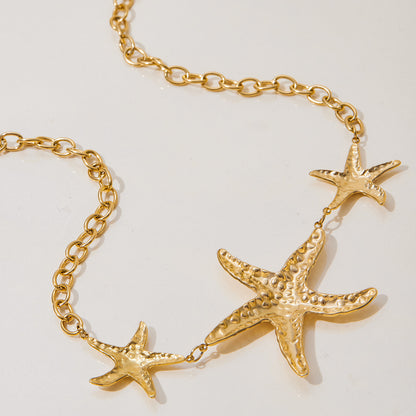 Detailed shot of golden hammered starfish necklace laid flat, emphasizing textured pendant and chunky chain