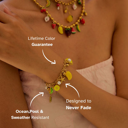 Gold fruit charm bracelet with mango and lemon pendants on model wrist