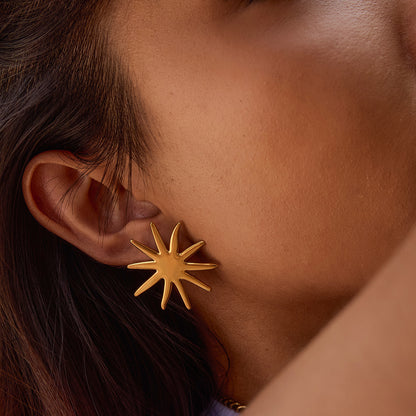 Close-up of golden star-shaped earrings styled on model with warm lighting