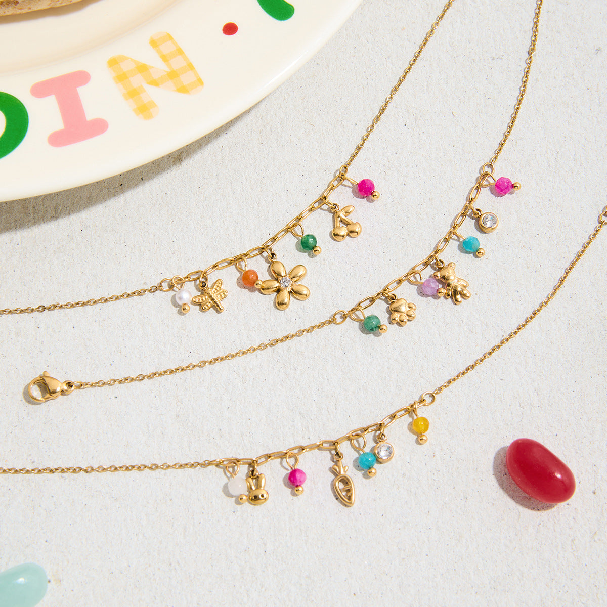 Close-up of gold charm bracelet with teddy, flower and beads