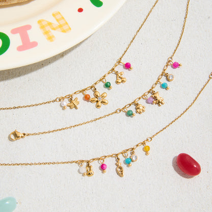 Close-up of gold charm bracelet with teddy, flower and beads