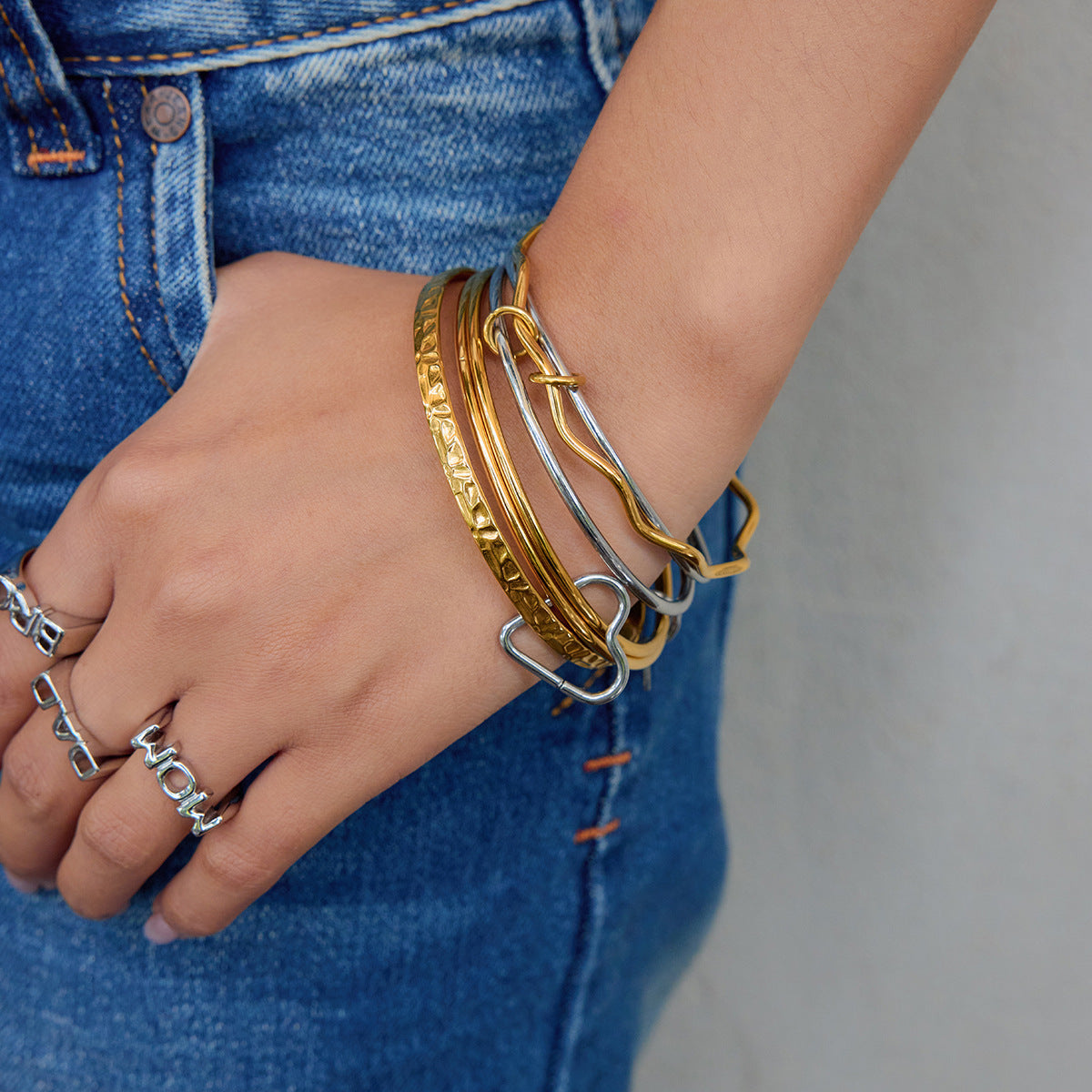 Model wearing gold and silver mixed charm bangles on wrist