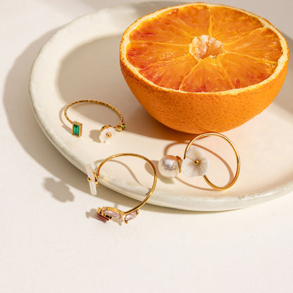Flat lay of gold flower rings with pearl and gemstone details