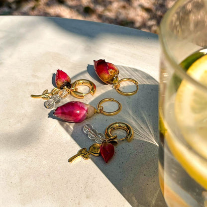 Summer earrings with preserved red rosebuds and gold charms in natural sunset light