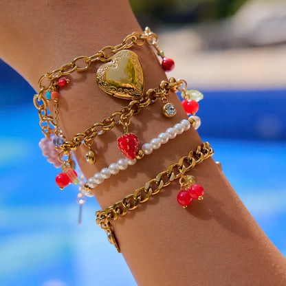 Layered gold bracelets including berry charm bracelet worn by model poolside in summer