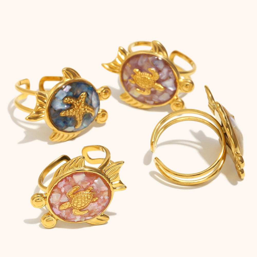 Back view of fish-shaped shell rings on sandy beige background