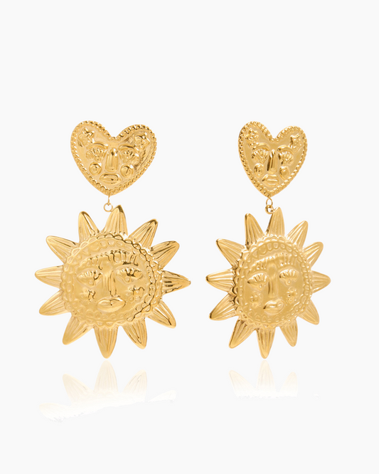 Gold heart and sun design earrings on a white background