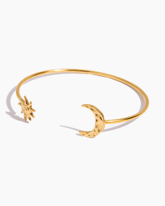 Gold bracelet with star and moon designs on a white background