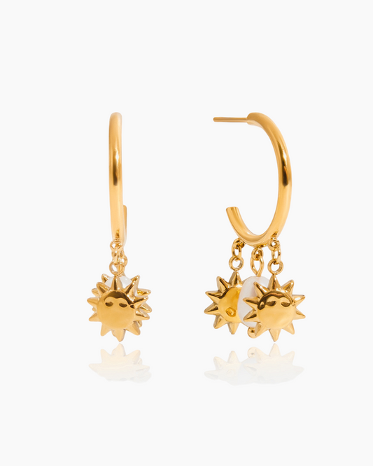 Gold hoop earrings with sun-shaped charms on a white background