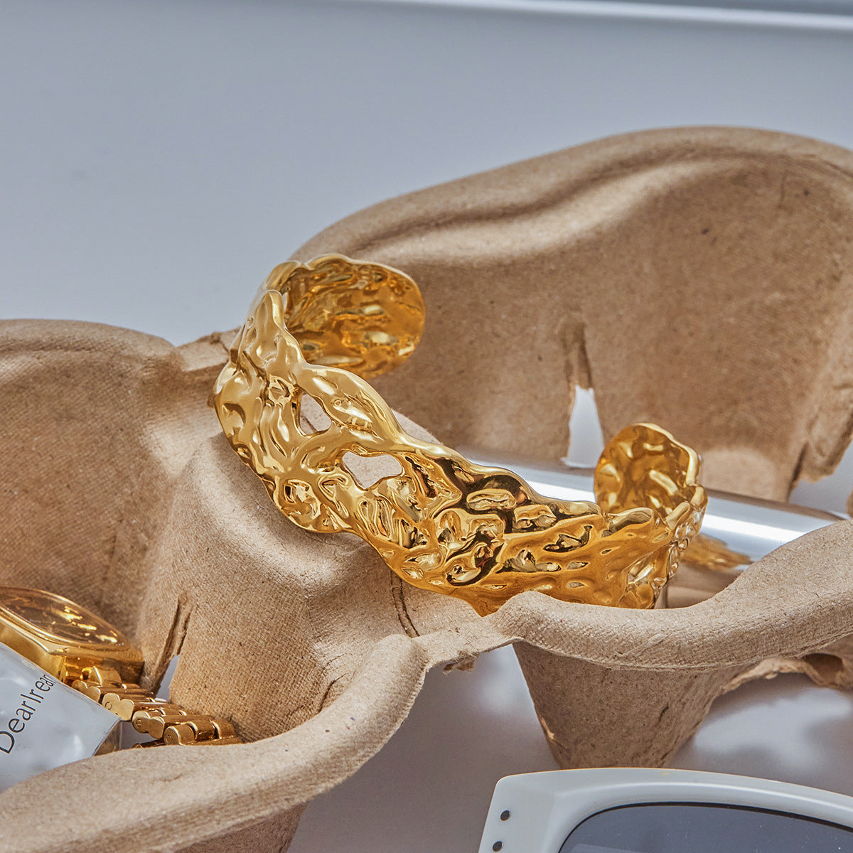 Golden cuff bracelet displayed on eco packaging with luxury accessories.