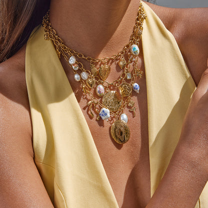 Close-up of a golden heart locket pendant resting on a model’s collarbone in soft sunlight.