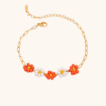 Orange and white daisy bracelet styled with gold chain on a soft surface