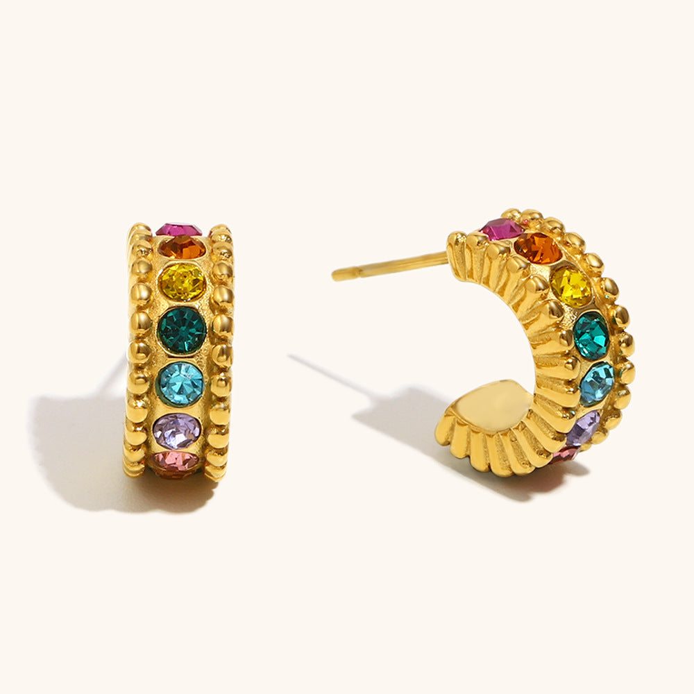Multicolor crystal gold huggie earrings styled on beige backdrop