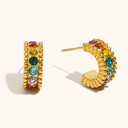 Multicolor crystal gold huggie earrings styled on beige backdrop