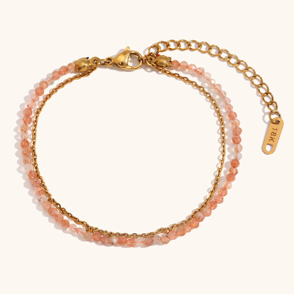 18K gold bracelet with sunset orange crystals and double-layer chain on neutral background.