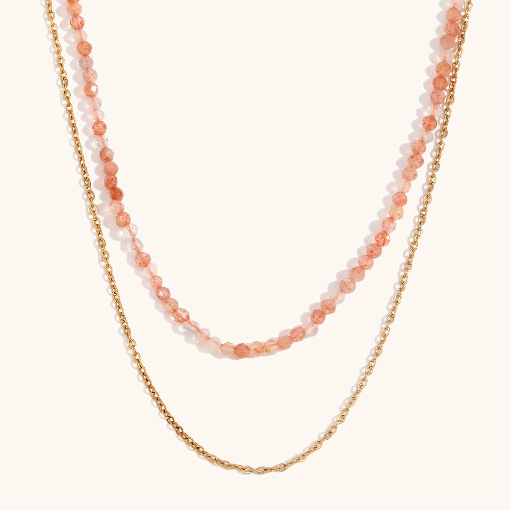 Orange crystal layered necklace with gold chain, displayed against peach backdrop