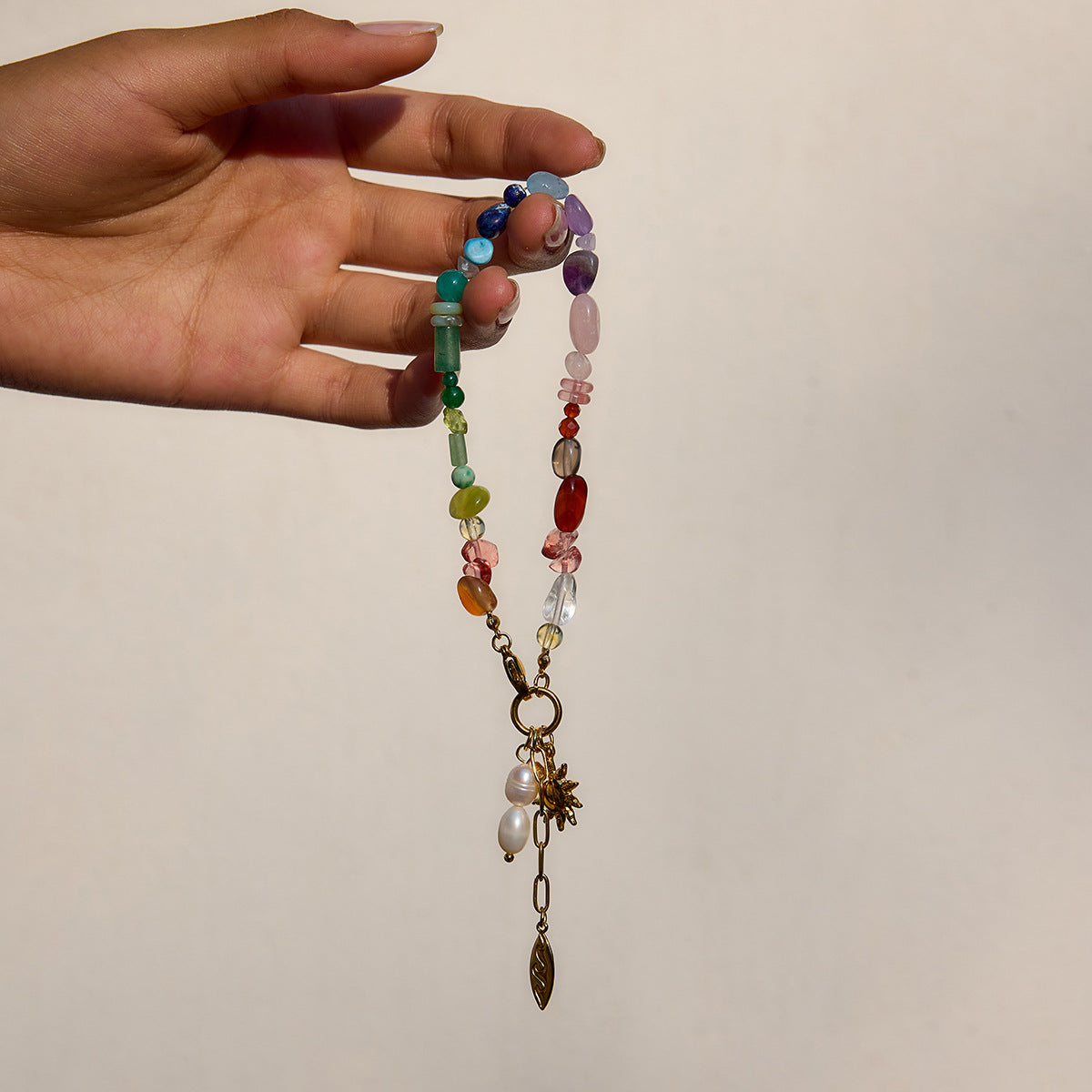 Colorful gemstone bracelet with sun charm on model's wrist by the pool