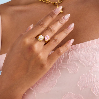 Floral gold ring on a woman's hand with fruit and pink dress background