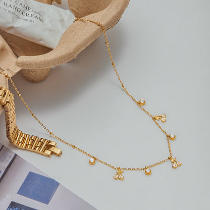Close shot of model pointing at cherry charm pendant necklace on collarbone
