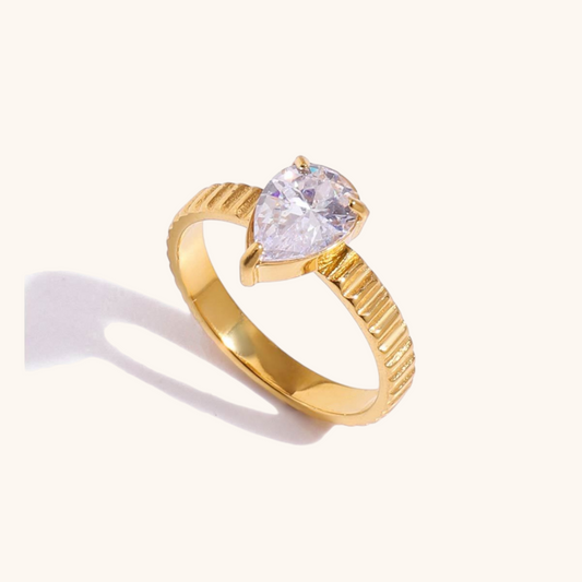 Teardrop-shaped gold ring with textured band and clear gemstone