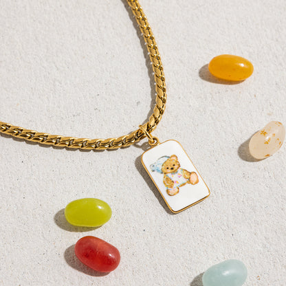 Bear charm necklace styled with candy elements on textured concrete background