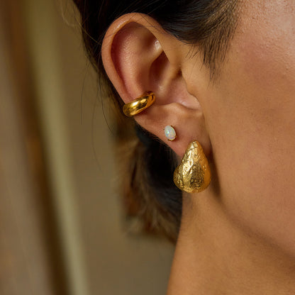 Gold statement earrings styled on model in indoor lighting