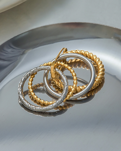 Gold and silver hoop earrings on a reflective surface