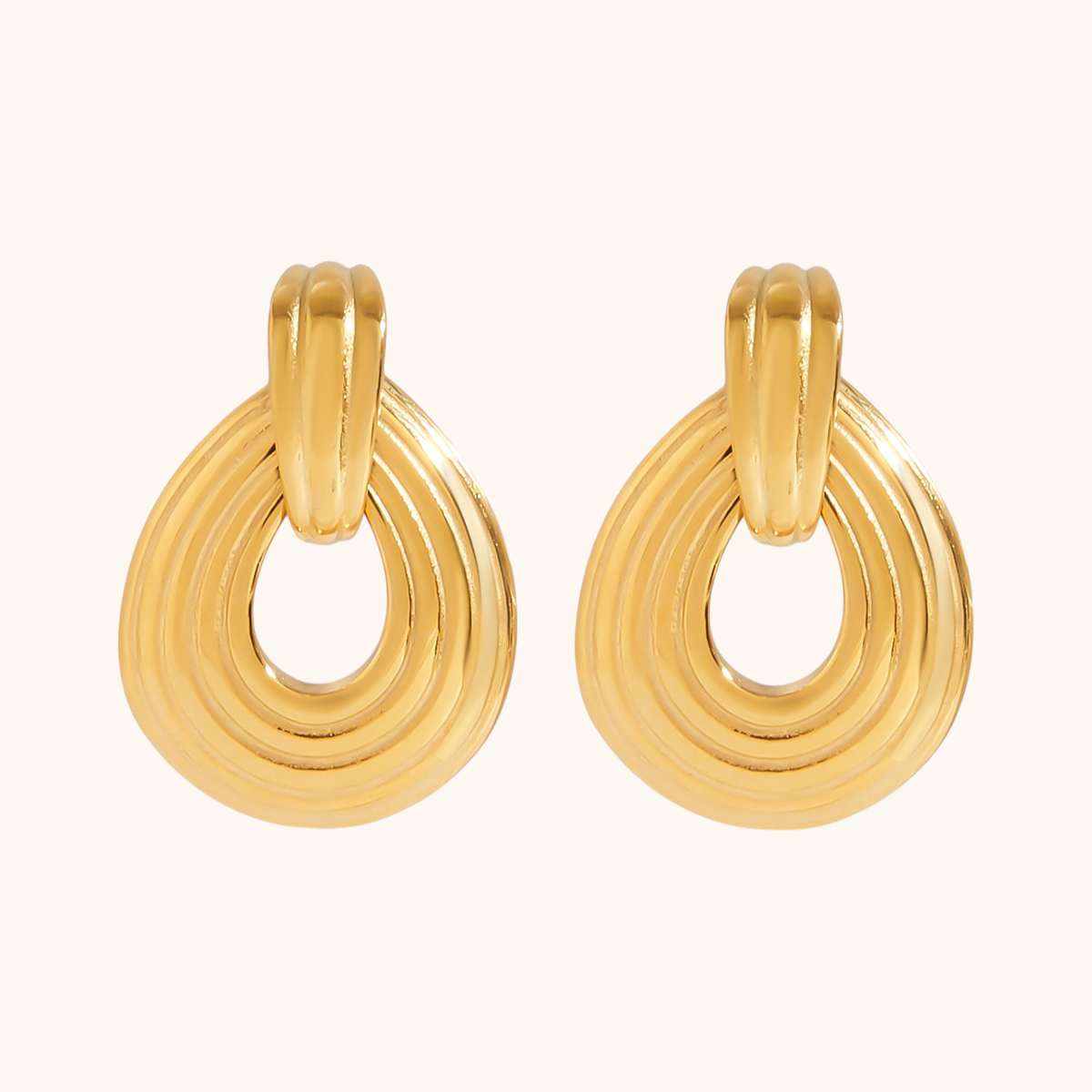 Pair of sculptural gold teardrop earrings on white background