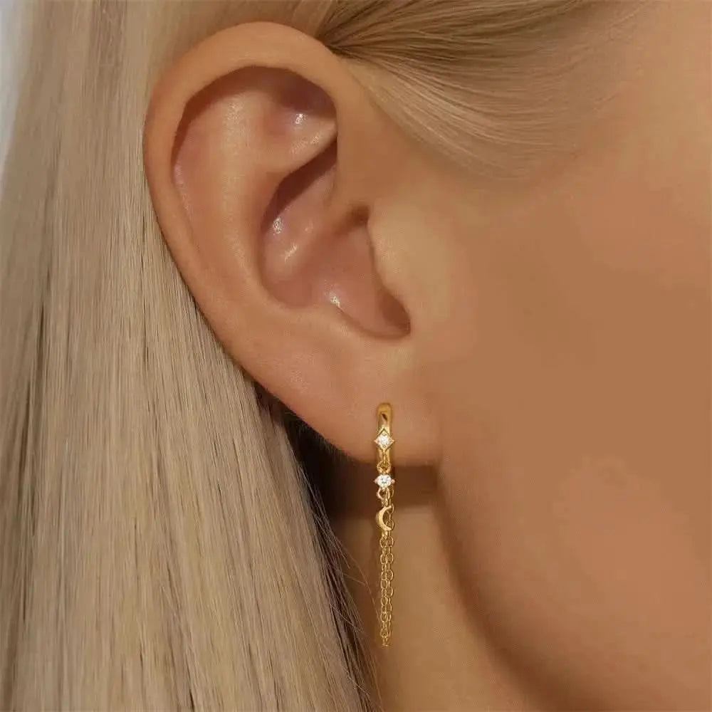 These celestial gold earrings feature elegant chain details and moon accents