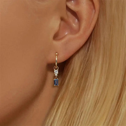 These delicate gold hoops with blue stones add a subtle pop of color to any outfit.