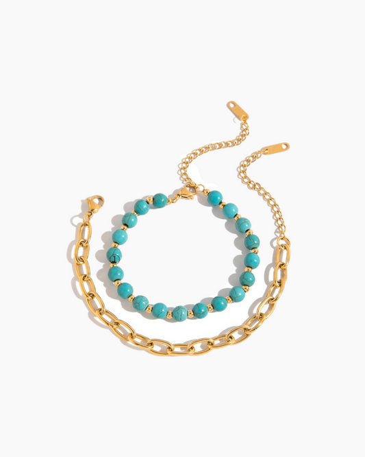 Two bracelets on a white background, one gold chain and one turquoise beads.