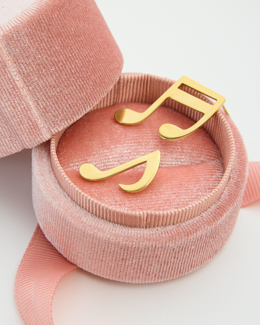Pink jewelry box with gold music note design on a white background