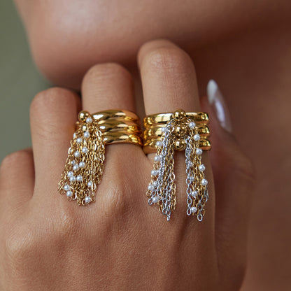 Model wearing layered chain tassel rings on both hands