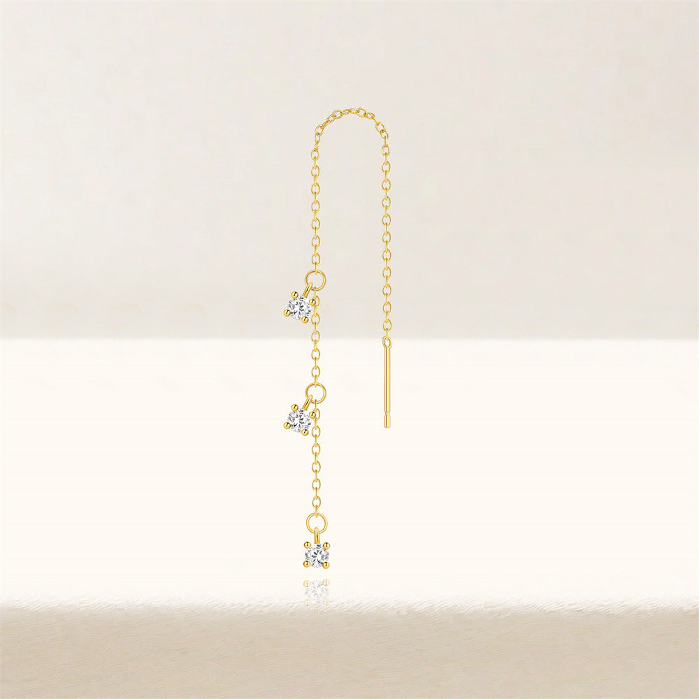 Close-up of minimalist gold threader earrings with three zircon stones on a model's ear