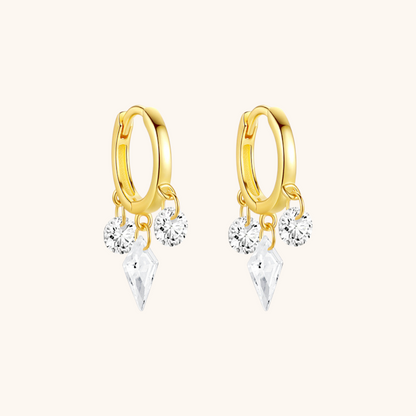 Close-up side view of gold hoop earrings with three cubic zirconia charms