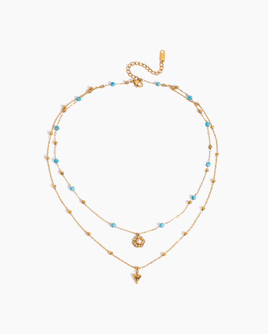 Two layered gold necklaces with blue beads on a white background