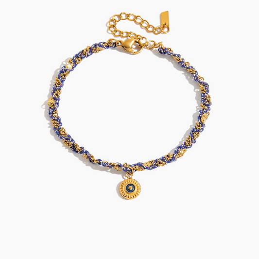 Gold and blue beaded bracelet with a round charm on a white background