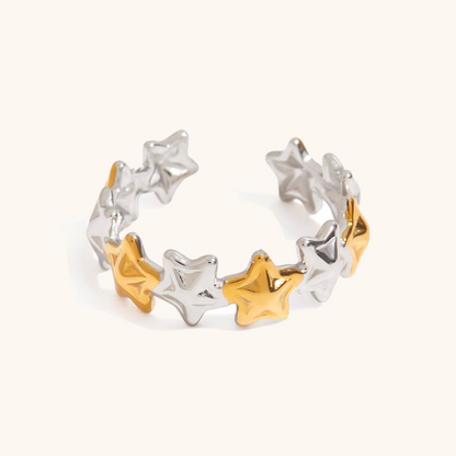 Silver and gold star ring with open band design on neutral background