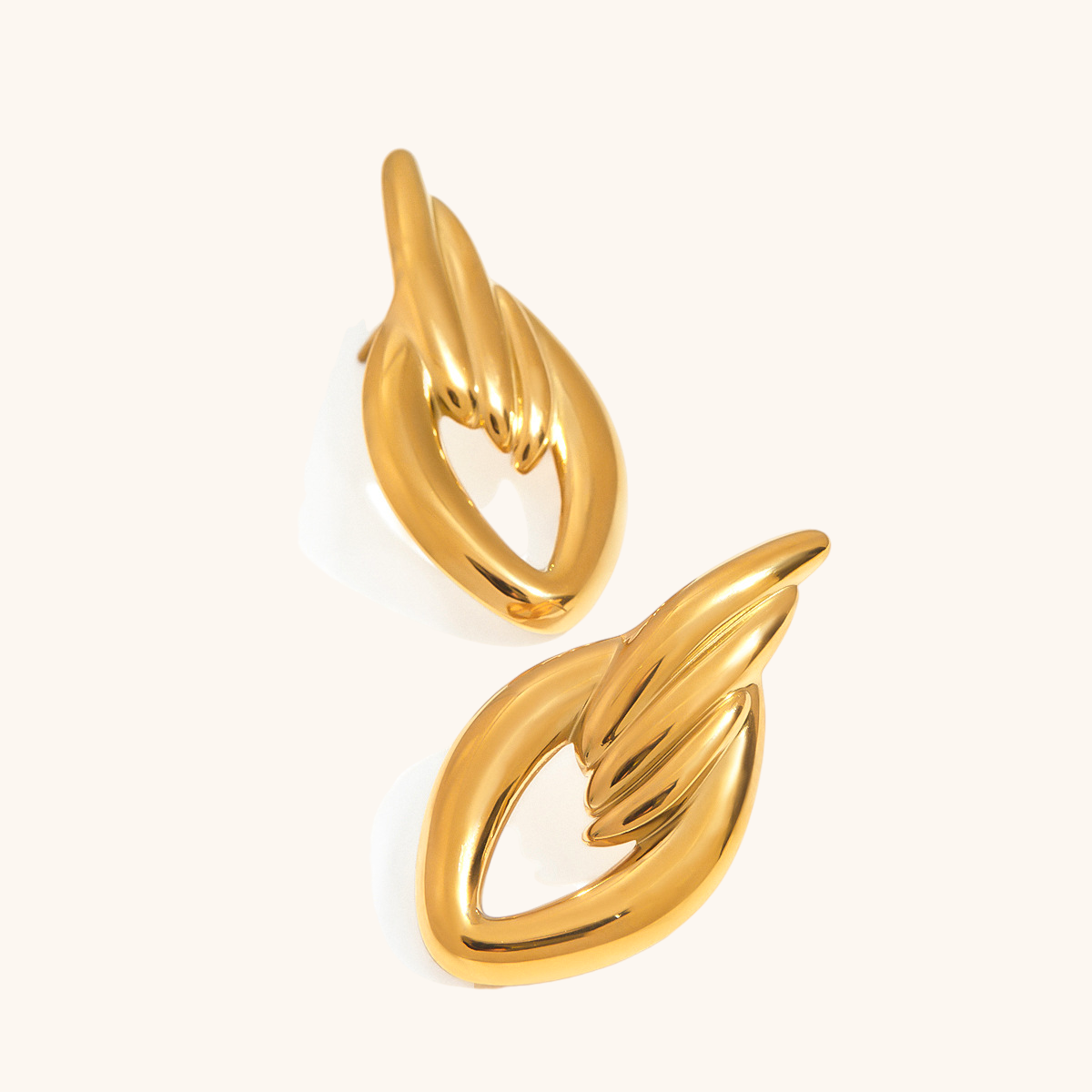 Chunky gold twisted wing earrings on white background
