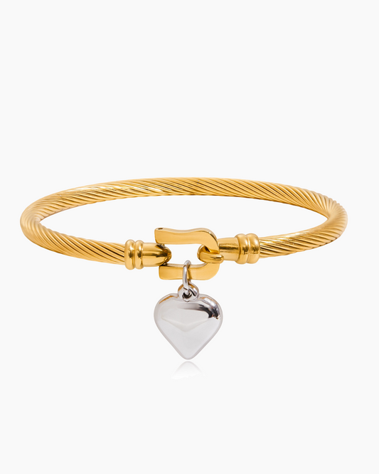Gold bracelet with a silver heart charm on a white background