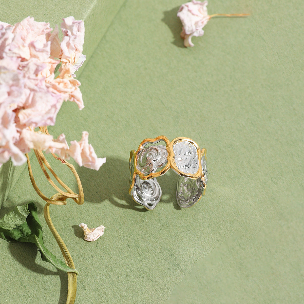 Two-tone open band ring with hammered and spiral textures, displayed with dried florals