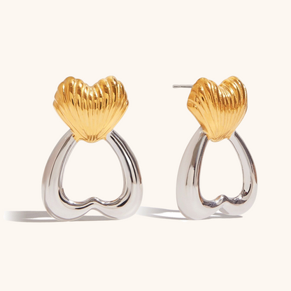 Close-up of gold and silver heart-shaped drop earrings with sculpted shell detail