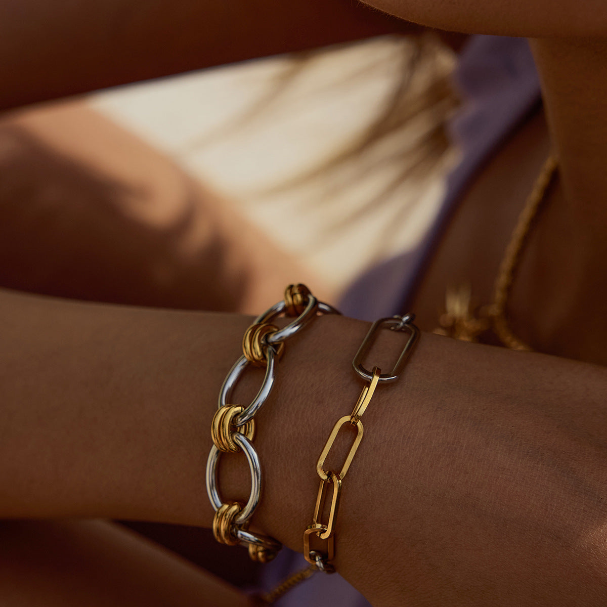 gold and silver mixed chain bracelet styled on wrist, paired with bold chunky chain
